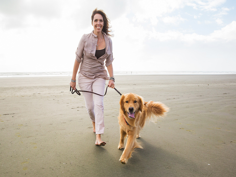 Woman walking a golden retriever dog at the beach on Jekyll Island